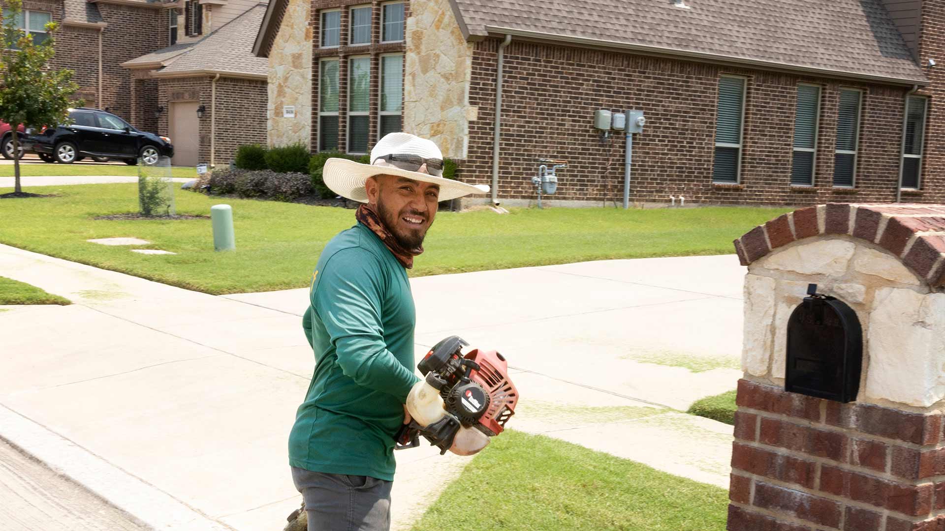 Smiling lawn care worker with weed eater in Wylie, TX.