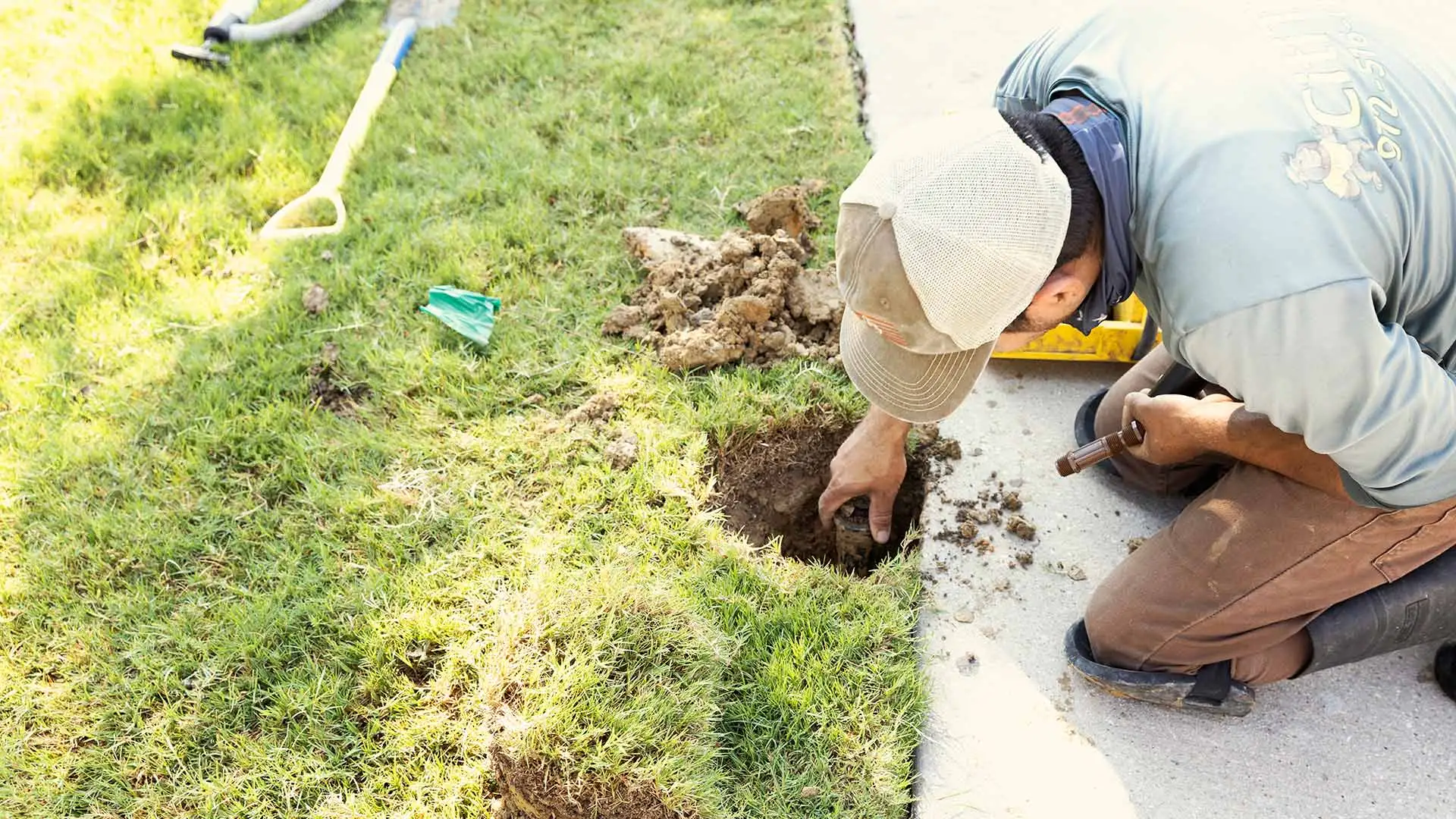 Technician repairing sprinkler system in lawn in Lucas, TX.