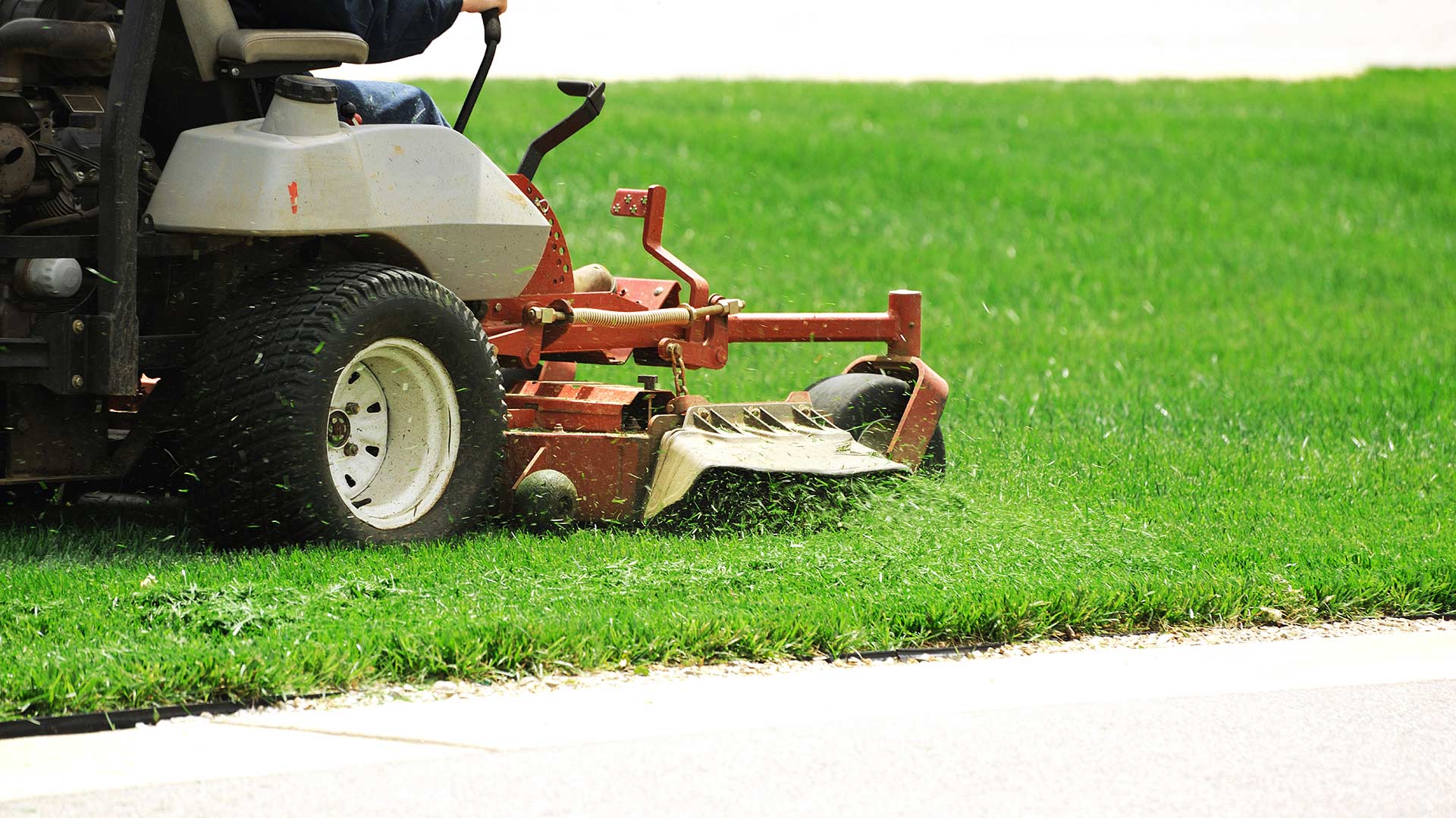 A lawn is being mowed by a large sit-down mower in Garland, TX.
