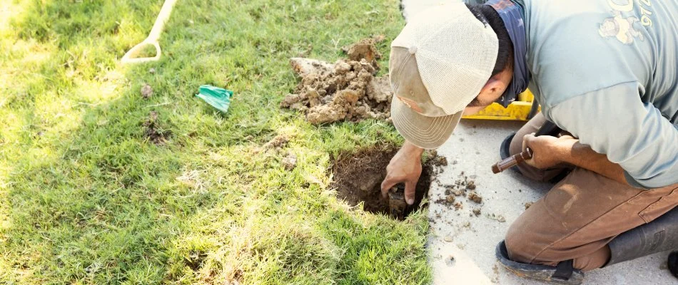 Irrigation technician inspecting and fixing a sprinkler in Plano, TX.