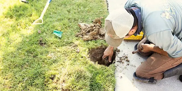 Irrigation pro repairing a sprinkler system in Frisco, TX.