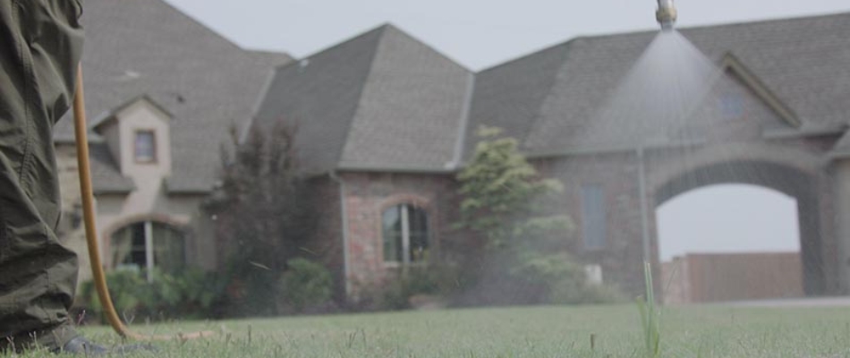 Lawn care technician spraying pest control on residential lawn in Allen, TX.