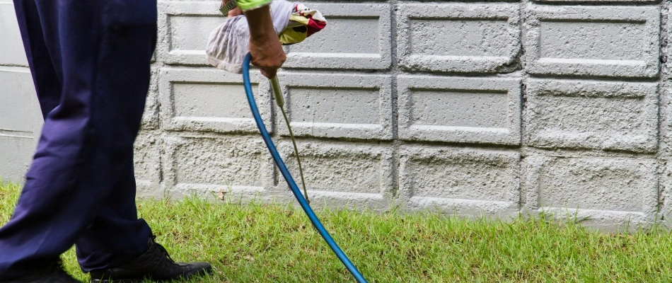 Professional applying perimeter pest control to foundation of a home in Wylie, TX.