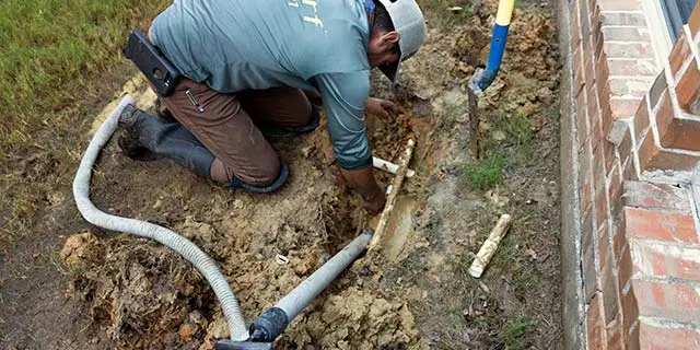 Irrigation professional repairing broken pipe at a home in Sachse, TX.